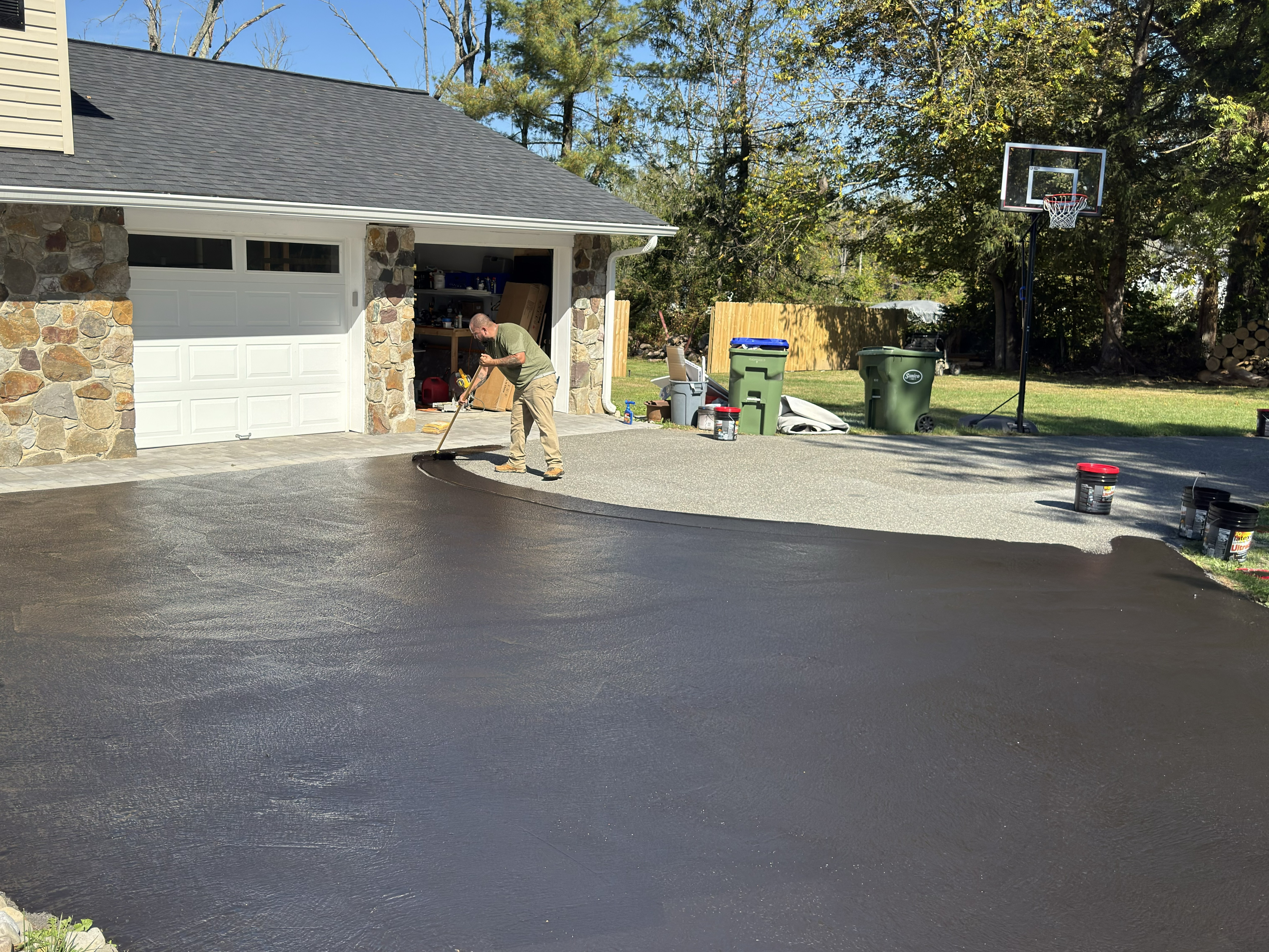 Applying black protectant to driveway
